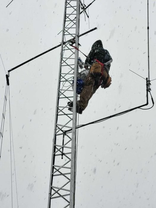 Harmen atop of the VE3KPG tower with dish installed in heavy snow.